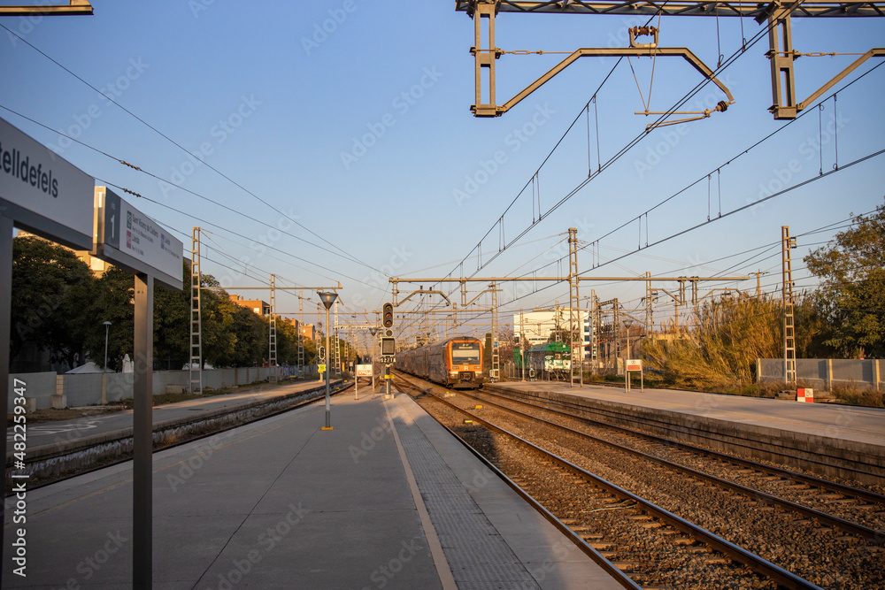 Rail travel. Modern intercity train on a railway platform. Passenger train on the railway in the evening. Railway station Castelldefels. Platform, rails and wires going into perspective.