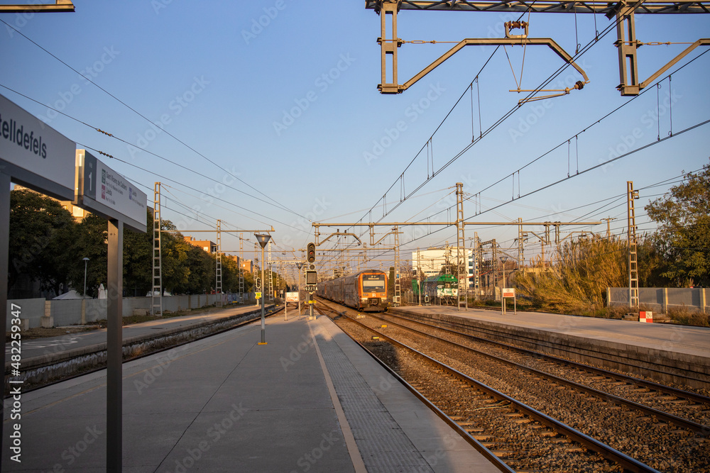 Rail travel. Modern intercity train on a railway platform. Passenger train on the railway in the evening. Railway station Castelldefels. Platform, rails and wires going into perspective. Rail travel. Modern intercity train on a railway platform. Passenger train on the railway in the evening. Railway station Castelldefels. Platform, rails and wires going into perspective.