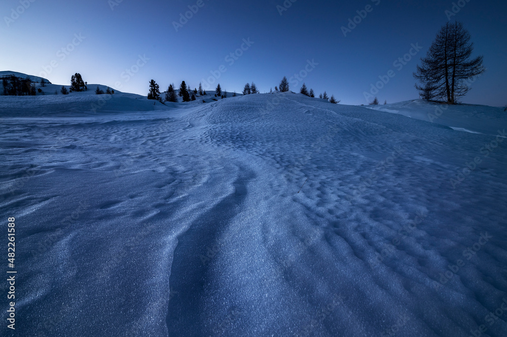 Shapes created by the wind in the snow in a blue morning in Cortina d'Ampezzo, in the italian dolomites
