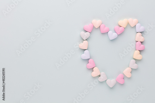 Composition with candy hearts on pastel blue background.