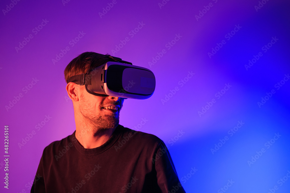 Man using VR virtual reality glasses. Futuristic metaverse universe games and future in digital technology. Entreatment and NFT in neon colorful space. Happy male. Slow motion video in 3d cyber space. Man using VR virtual reality glasses. Futuristic metaverse universe games and future in digital technology. Entreatment and NFT in neon colorful space. Happy male. Slow motion video in 3d cyber space.