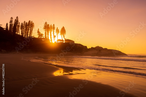 Bright sunrise on ocean with waves and rocks. Joaquina beach in Brazil