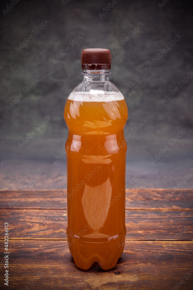 Plastic bottle of light beer lidded on brown wooden table on dark background