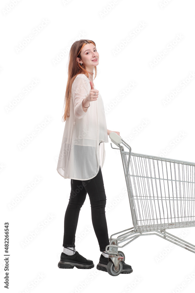 Happy young woman with shopping cart trolley in sale season