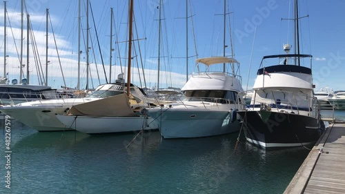 Different small boats moored in marina, blue sky and sea