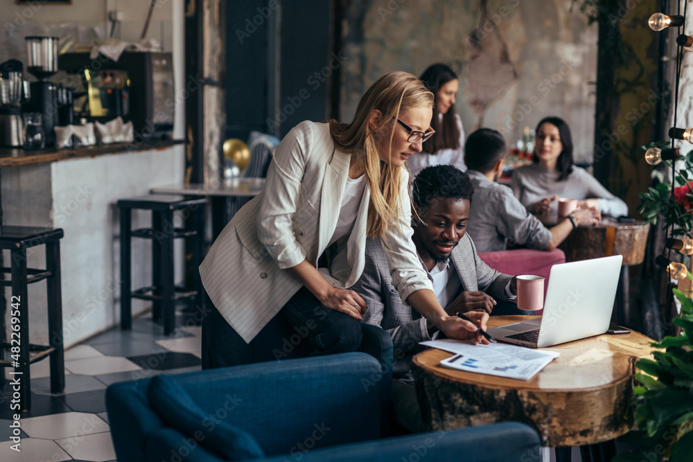 Black man works in cafe and discusses information from documents with woman Black man works in cafe and discusses information from documents with woman