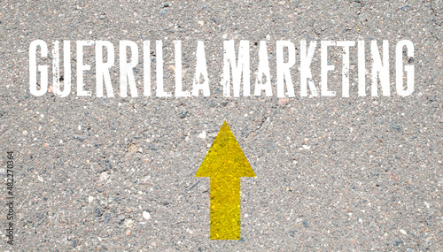 Bild auf Leinwand the inscription Guerrilla Marketing and an arrow on the asphalt background