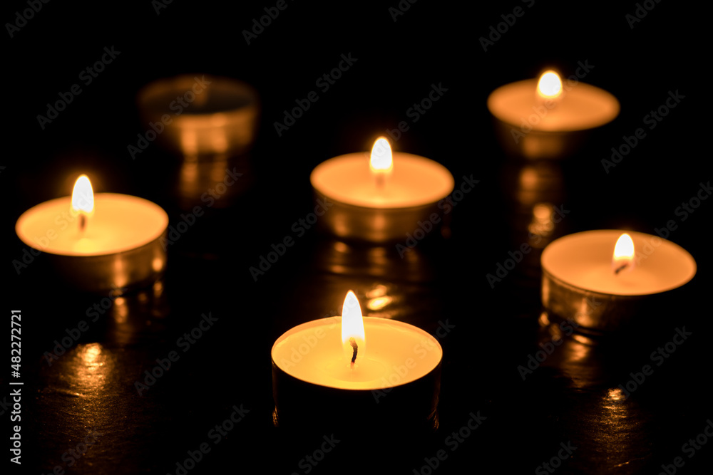 Five candles Burning out of six on dark table, black background, Memory day.