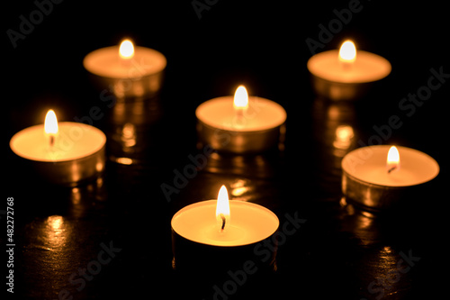 Burning candles on dark table  black background  Memory day.