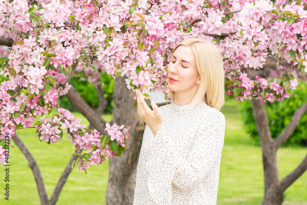 Young woman among the blossoming trees. Spring nature park or garden, flowering trees. Concept spring woman health Young woman among the blossoming trees. Spring nature park or garden, flowering trees. Concept spring woman health