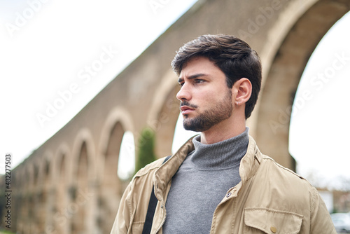 Thoughtful bearded man standing against arched wall