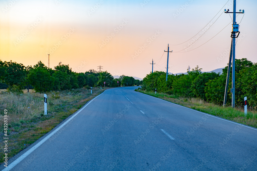 Fototapeta premium at sunset an asphalt road goes towards the mountains