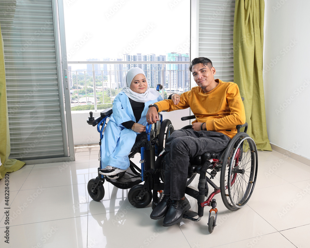 South east Asian malay man woman couple headscarf tudung middle aged disabled on wheelchair looking sitting in front of balcony window South east Asian malay man woman couple headscarf tudung middle aged disabled on wheelchair looking sitting in front of balcony window