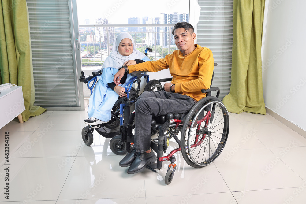 South east Asian malay man woman couple headscarf tudung middle aged disabled on wheelchair looking sitting in front of balcony window South east Asian malay man woman couple headscarf tudung middle aged disabled on wheelchair looking sitting in front of balcony window