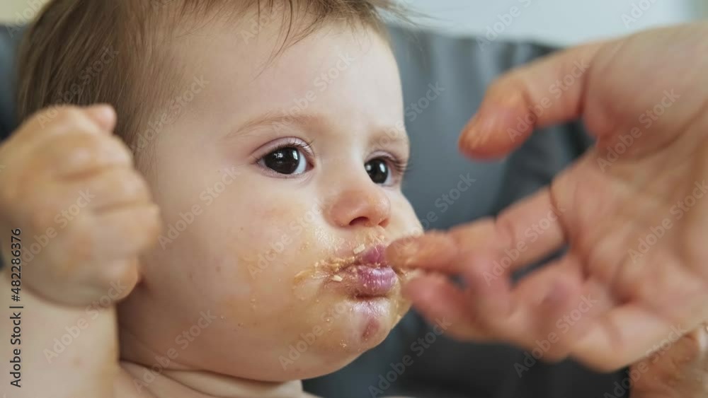 Video with mom's hands giving homogenized food to her daughter. Baby girl covering his face with his hands and frowning