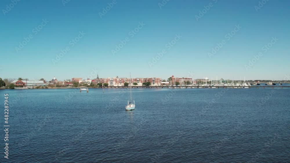 Drone shot of downtown New Bern North Carolina, over the trent river with a sail boat anchored in the water Drone shot of downtown New Bern North Carolina, over the trent river with a sail boat anchored in the water