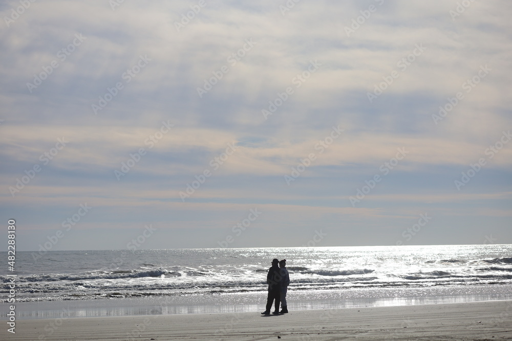 冬の海を見つめる男女のシルエット