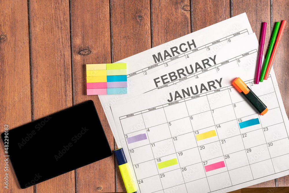 Calendar for the first months of the year together with a digital tablet and colorful adhesive note to highlight the most important activities to be carried out during the month. Concept plans and Calendar for the first months of the year together with a digital tablet and colorful adhesive note to highlight the most important activities to be carried out during the month. Concept plans and