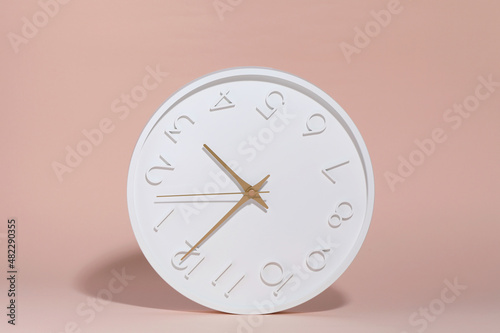 A white circle watch against a pink background.