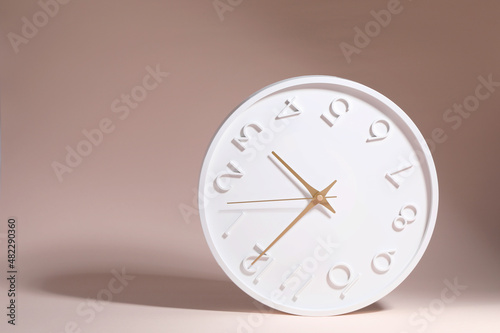 A white circle watch against a pink background.