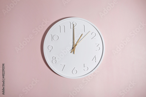 A white circle watch against a pink background.