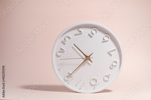 A white circle watch against a pink background.