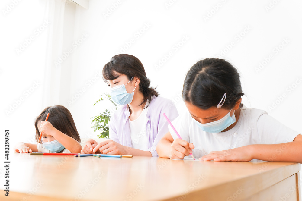 マスクを付けて勉強をする子供と塾講師