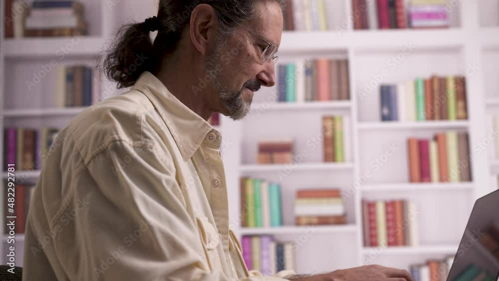 Happy smiling mature smart man in eyeglasses calculating expenditures, business profit, managing household budget, paying utility bills or taxes online using e-banking application on computer at home Happy smiling mature smart man in eyeglasses calculating expenditures, business profit, managing household budget, paying utility bills or taxes online using e-banking application on computer at home