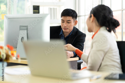 Asian business man and woman meeting analyzing and discussing strategy with startup project.Creative business people plan and brainstorm with laptop computer on conference in office.Teamwork