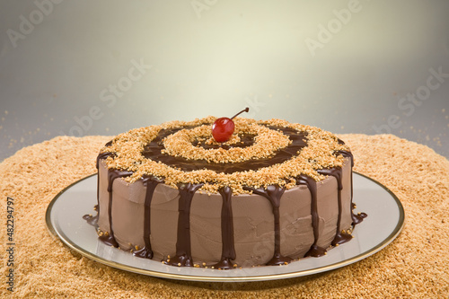 Bolo de chocolate com uma cereja em cima com noz triturado...