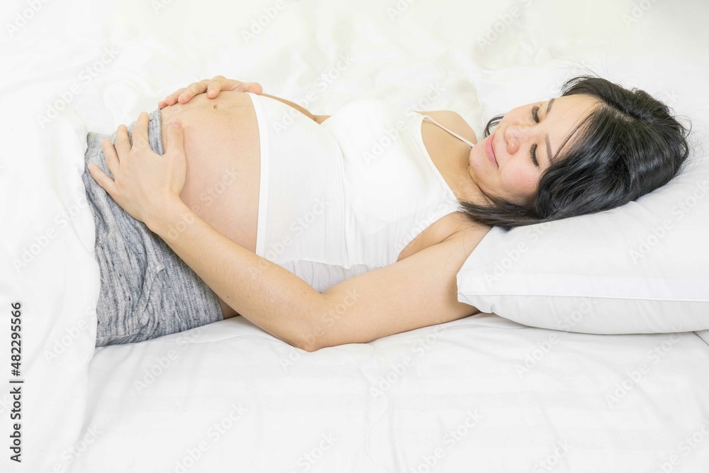 pregnancy, rest, people and expectation concept - happy asian pregnant woman sleeping peacefully in bed at home. pregnancy, rest, people and expectation concept - happy asian pregnant woman sleeping peacefully in bed at home.