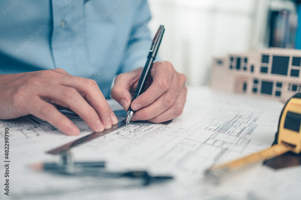 Architect engineer use pen and angle protector drawing design working on bueprint. House planning design and construction concept. Architect engineer use pen and angle protector drawing design working on bueprint. House planning design and construction concept.