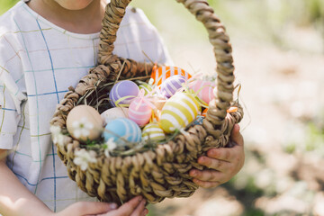 Easter egg hunt in spring garden. Funny boy with eggs basket and bunny ears on Easter egg hunt in sunny spring garden. Children celebrating Easter. Happy easter card