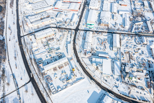 cityscape with industrial enterprises in sunny winter day. buildings covered with fresh snow. aerial view.