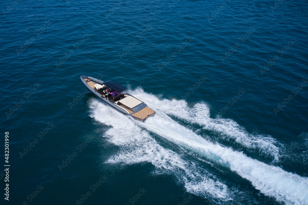 Naklejka premium Dark gray blue boat in motion at sea. Boat drone view. Speedboat moving fast on blue water aerial view.
