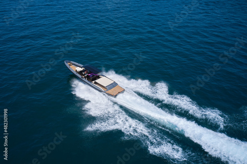 Dark gray blue boat in motion at sea. Boat drone view. Speedboat moving fast on blue water aerial view.