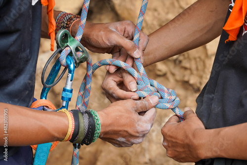 Close up shot of preparation before climbing a cliff. Symbol of teamwork to make sure the safety of teammate