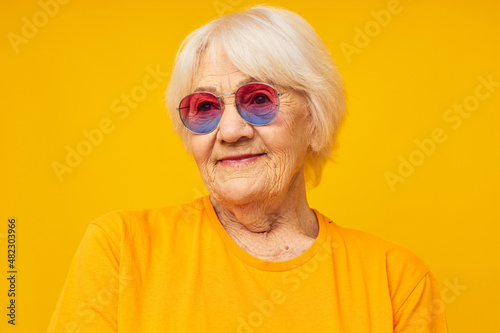 Photo of retired old lady in a yellow t-shirt posing yellow background