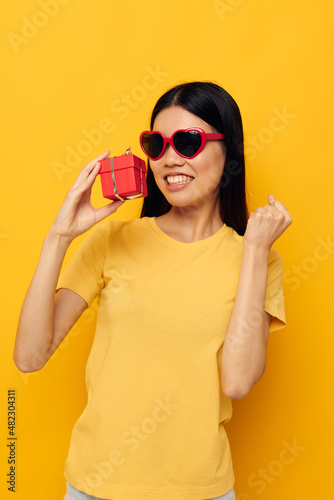 woman with Asian appearance with gift boxes in hands fun posing yellow background unaltered