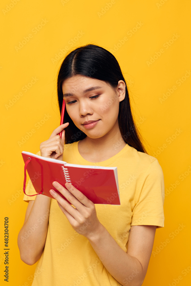 woman with Asian appearance in a yellow t-shirt red notebook training studio model unaltered woman with Asian appearance in a yellow t-shirt red notebook training studio model unaltered