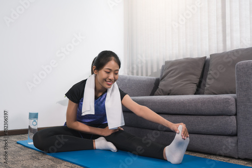Asian women do stretching exercises after taking yoga classes while at home.