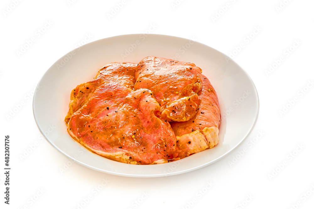 Pork in marinade lies on a white plate on a white isolated background Pork in marinade lies on a white plate on a white isolated background