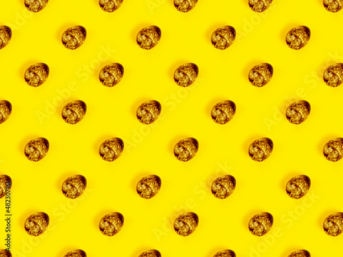 The easter background with the quail brown eggs pattern on the trendy yellow background.