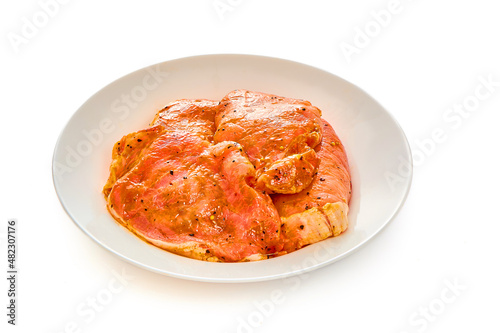Pork in marinade lies on a white plate on a white isolated background