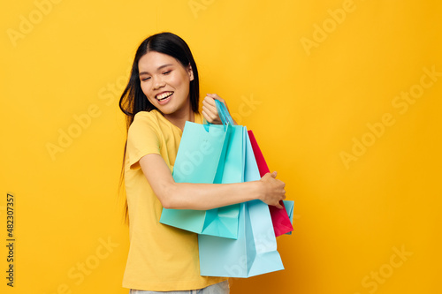 pretty brunette in a yellow T-shirt with multicolored shopping bags studio model unaltered