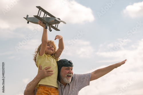 Quadro su tela Excited child boy and grandfather having fun with plane outdoor on sky background with copy space