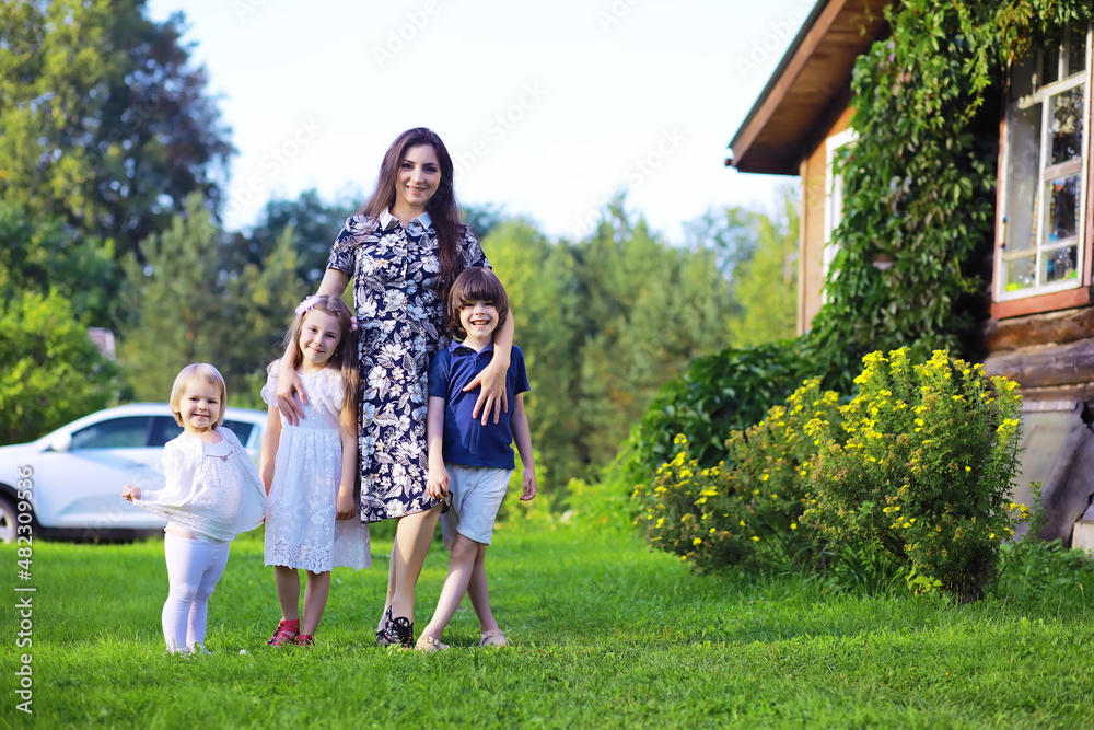 Obraz premium Young large family on a summer morning walk. Beautiful mother with children is playing in the park.