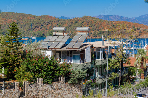 A lot of solar water heating systems on roof of cottage. A lot of large water tanks and solar panels on roof. Horizontal photo. © Vladimir Kazakov