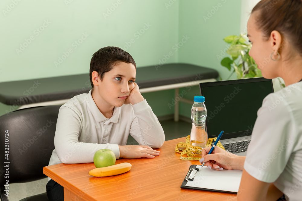 Doctor advising a fat boy to eat healthy. Child eating stealthily high calorie foods. Obesity, health problem, weight loss. Prescribing diet for overweight fat patient. Doctor warning of consequences.