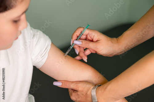 Vaccinations for children, immunization, disease prevention. Nurse with syringe vaccinating teenager with anti-virus vaccine injection in hospital. Vaccination and covid prevention. Injecting COVID-19